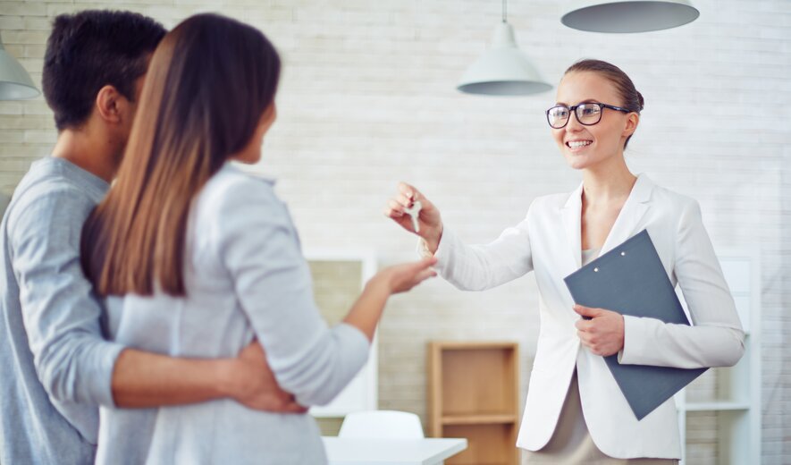 Maklerin übergibt einem Paar den Schlüssel zu einer Immobilie