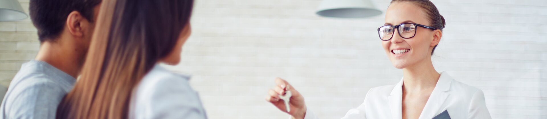 Maklerin übergibt einem Paar den Schlüssel zu einer Immobilie