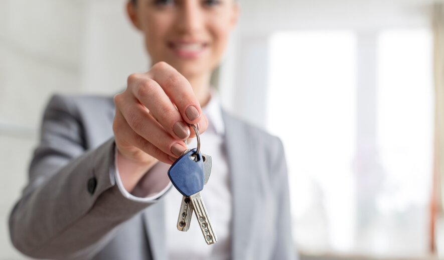 Maklerin übergibt neuen Wohnungsschlüssel an Kundin oder Kunden