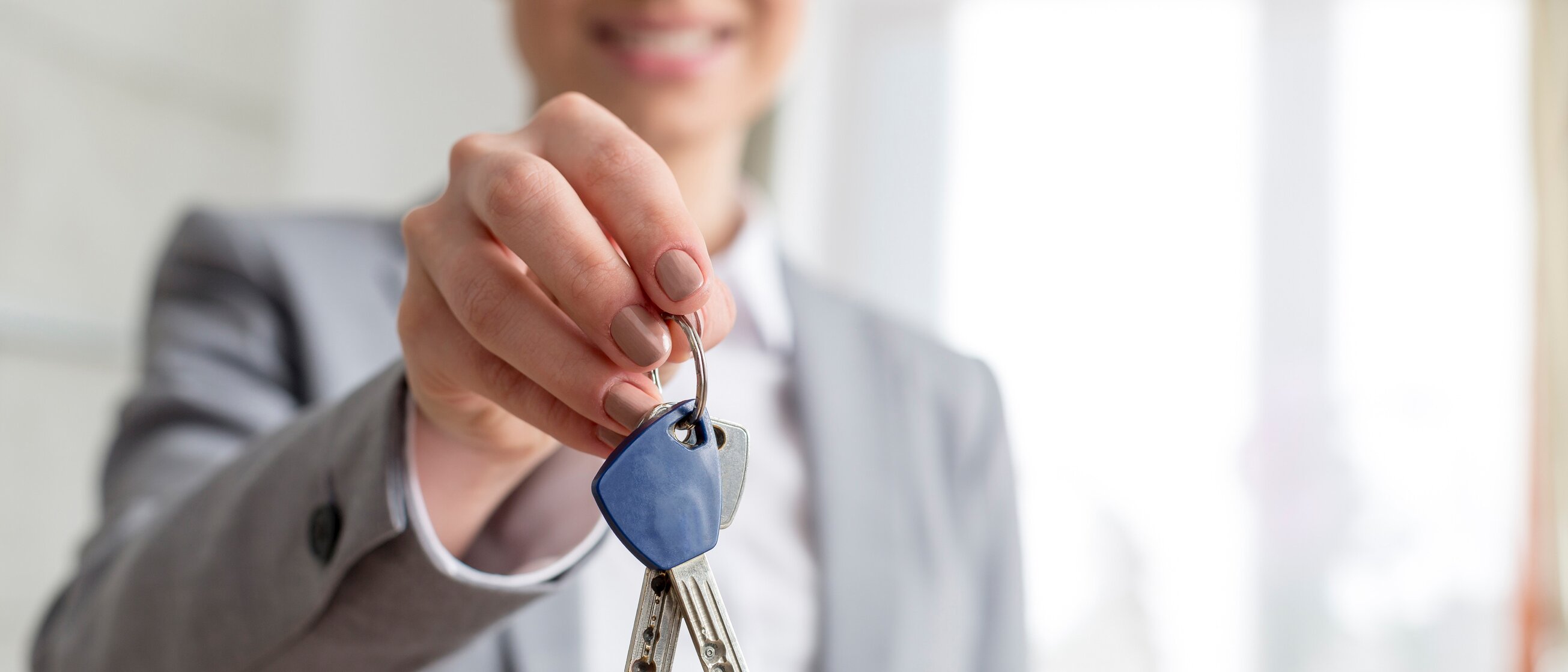 Weiterbildung für Immobilienmakler/-innen: Ein Immobilienmaklerin hält Schlüssel bei der Wohnungsübergabe