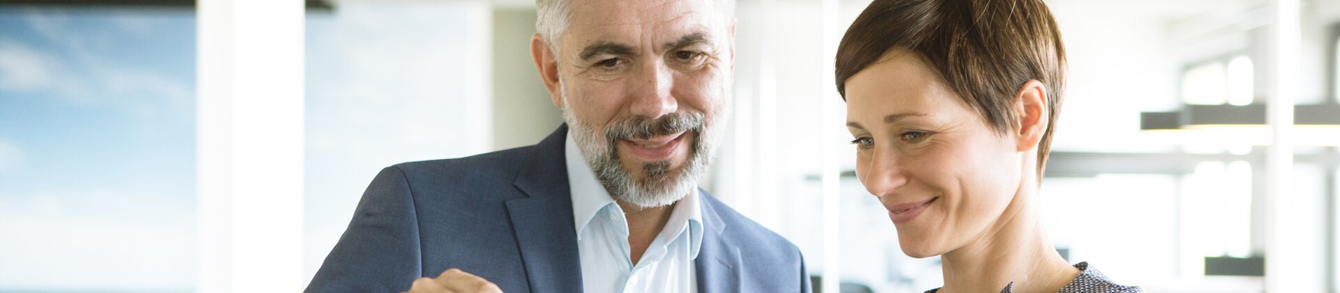 Zwei Geschäftsleute betrachten gemeinsam ein Tablet im modernen Büro