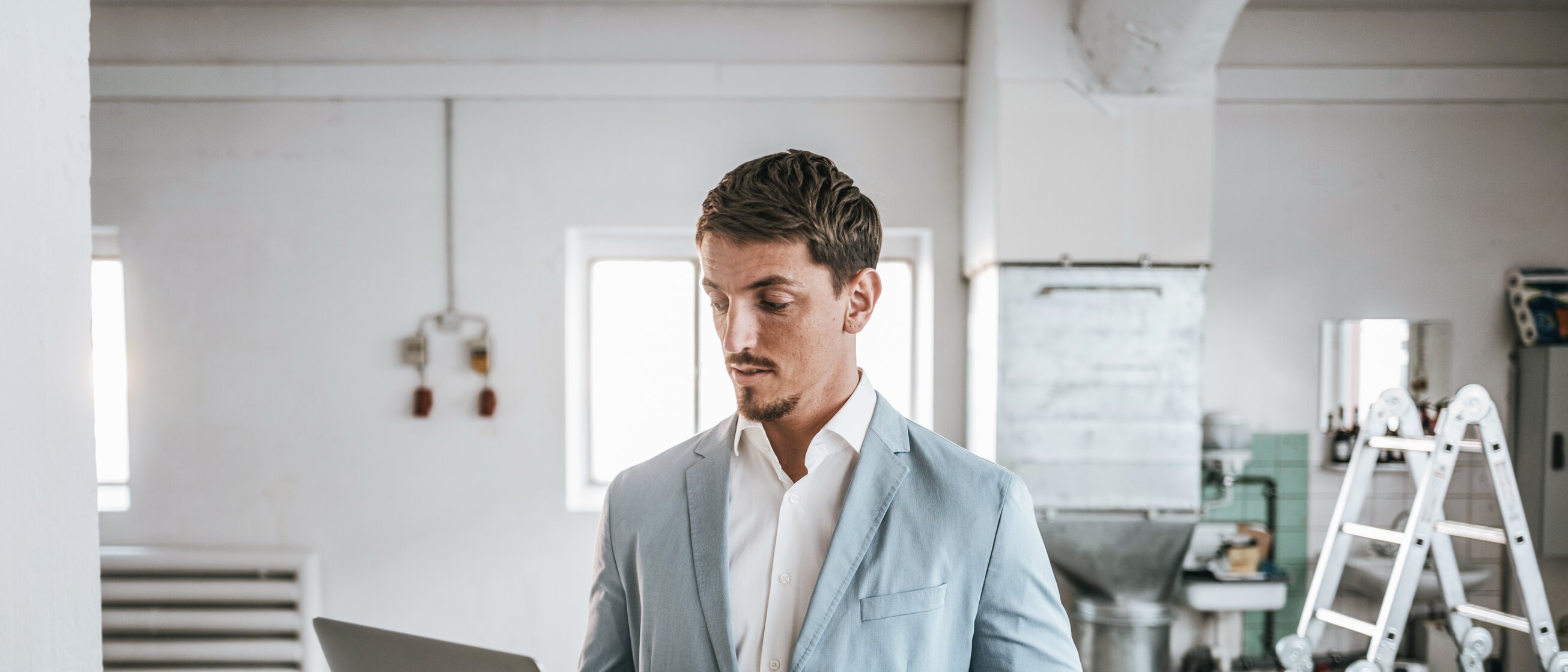 Weiterbildung im Bereich Immobilienmanagement: Ein Mann arbeitet konzentriert an einem Laptop in einem hellen, renovierten Raum.