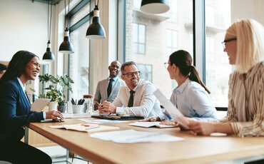 Team aus Immobilienfachleuten bespricht Unterlagen in einem modernen Büro – Weiterbildung im Immobilienmanagement