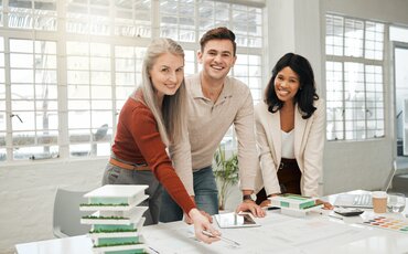 WeiterbilduDrei Personen arbeiten gemeinsam an Dokumenten – Weiterbildung im Bereich Immobilienverwaltungngen im Bereich Immobilienverwaltung: Drei Mitarbeiter arbeiten an einem Immobilienentwurf