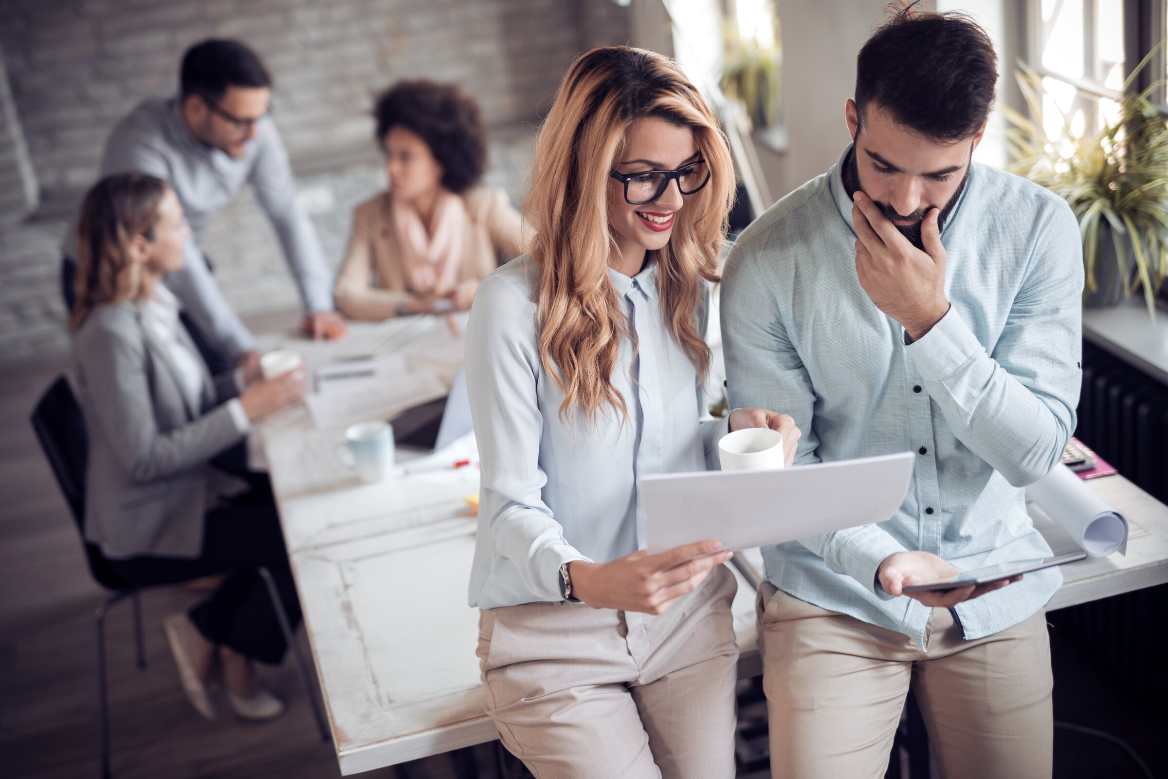 Mitarbeitende in einem modernen Büro besprechen Unterlagen – symbolisch für Aufstiegsmöglichkeiten und Gehaltssteigerung durch die Weiterbildung zum Industriemeister Chemie.