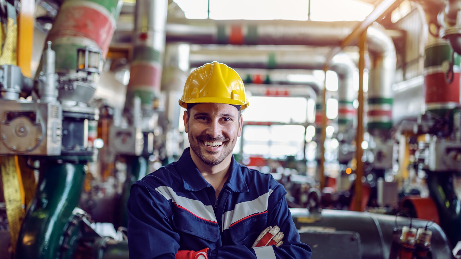 Industriearbeiter mit Schutzhelm lächelt in moderner Produktionsanlage