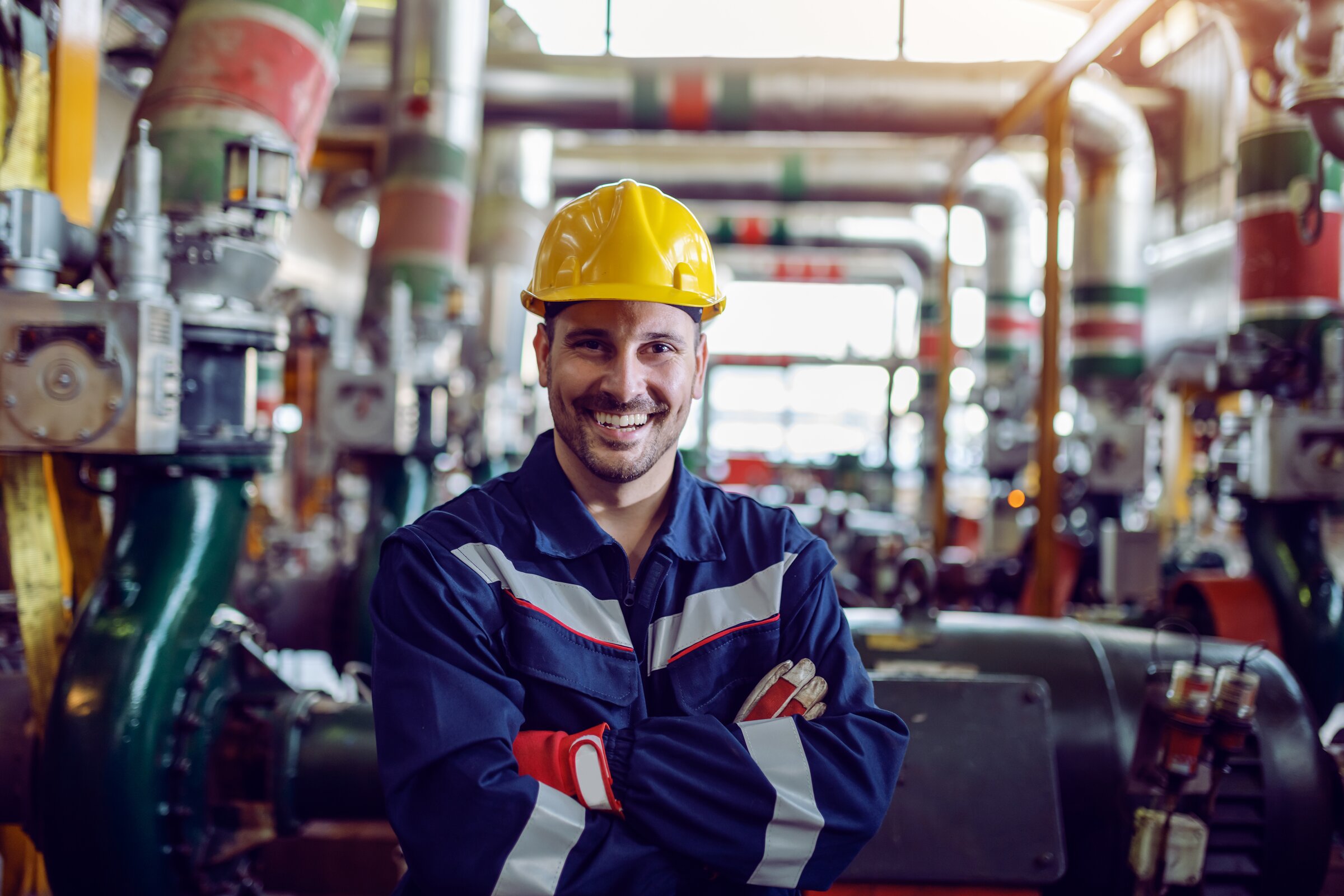 Industriearbeiter mit Schutzhelm lächelt in moderner Produktionsanlage
