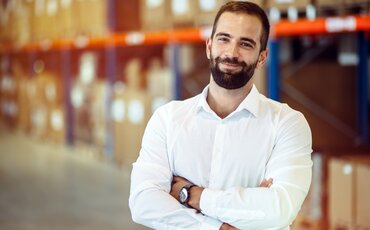 Logistikmeister in moderner Lagerhalle mit Regalsystemen – Weiterbildung Gepr. Logistikmeister/-in bei der IHK Akademie München und Oberbayern.
