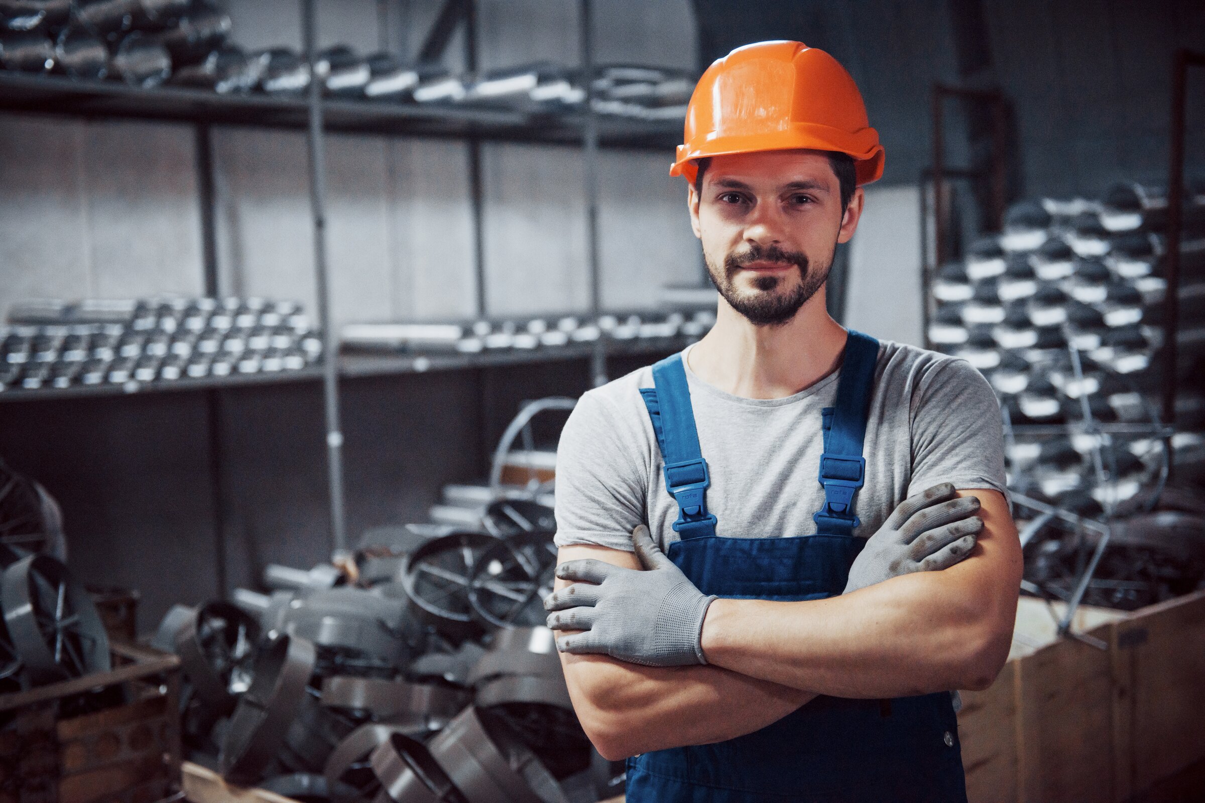 Mann mit Schutzhelm und verschränkten Armen in einer Werkhalle – Symbolbild für die Weiterbildung zum Geprüften Industriemeister Metall an der IHK Akademie Ingolstadt.