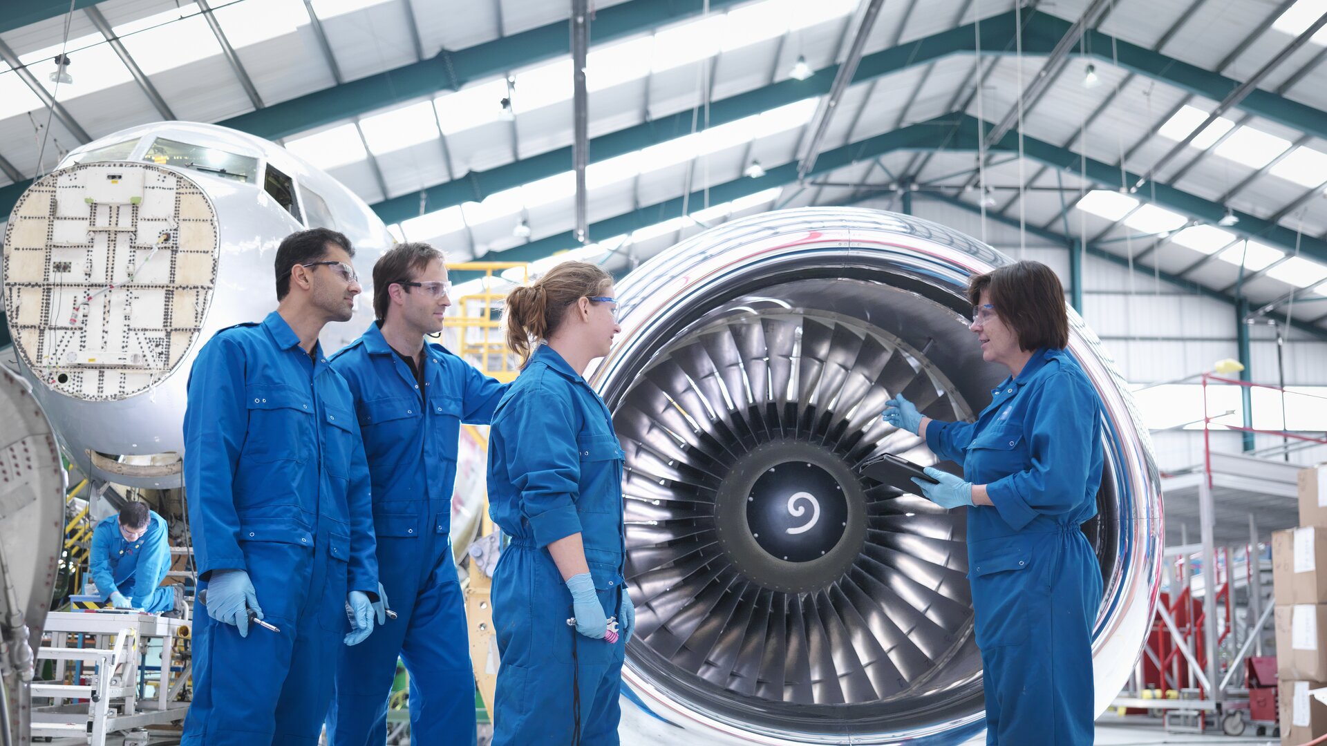 Technikerteam inspiziert großes Flugzeugtriebwerk in einer Werkhalle