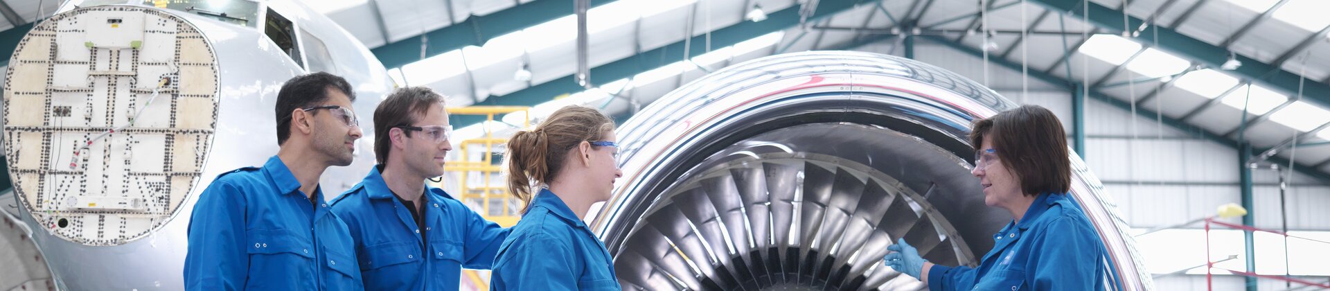 Technikerteam inspiziert großes Flugzeugtriebwerk in einer Werkhalle