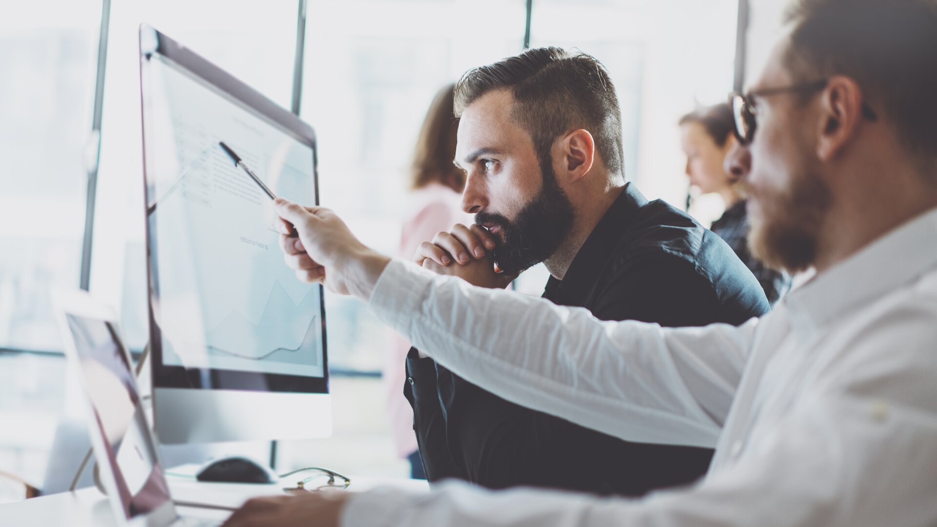 Team analysiert Daten und Diagramme am Computer im modernen Büro.