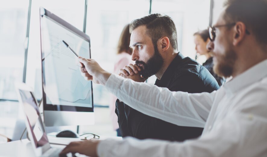 Team analysiert Daten und Diagramme am Computer im modernen Büro.