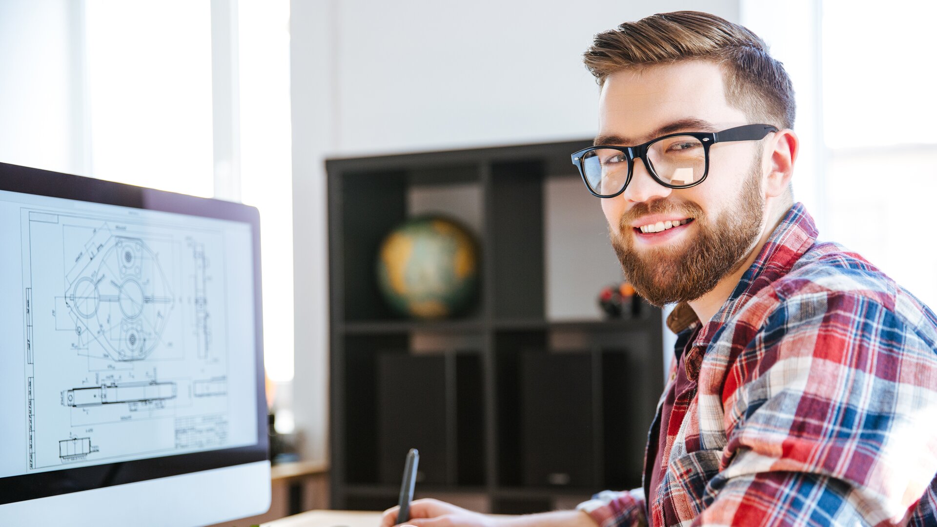 Junger Ingenieur arbeitet am Computer an technischen CAD-Zeichnungen im modernen Büro