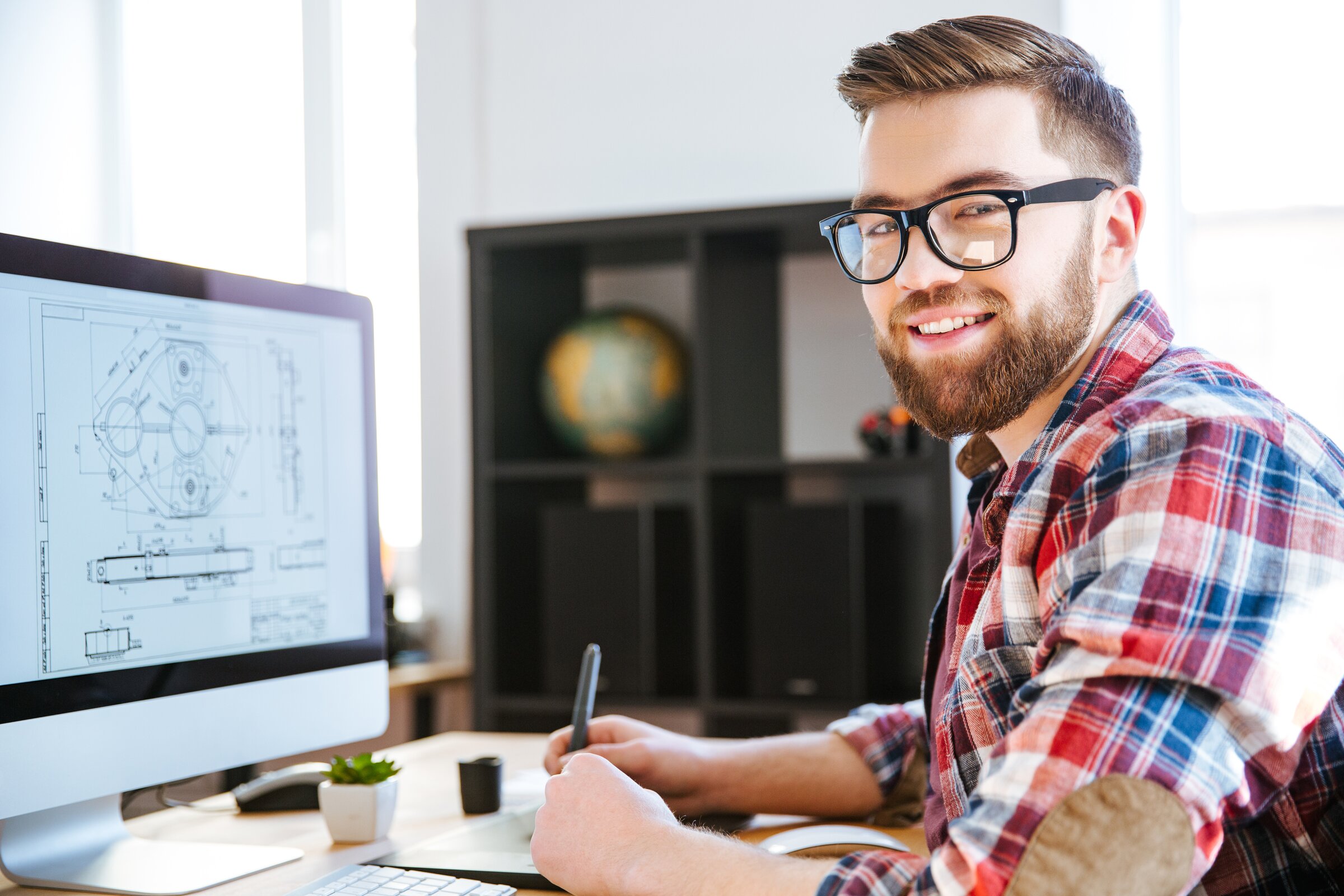 Junger Ingenieur arbeitet am Computer an technischen CAD-Zeichnungen im modernen Büro