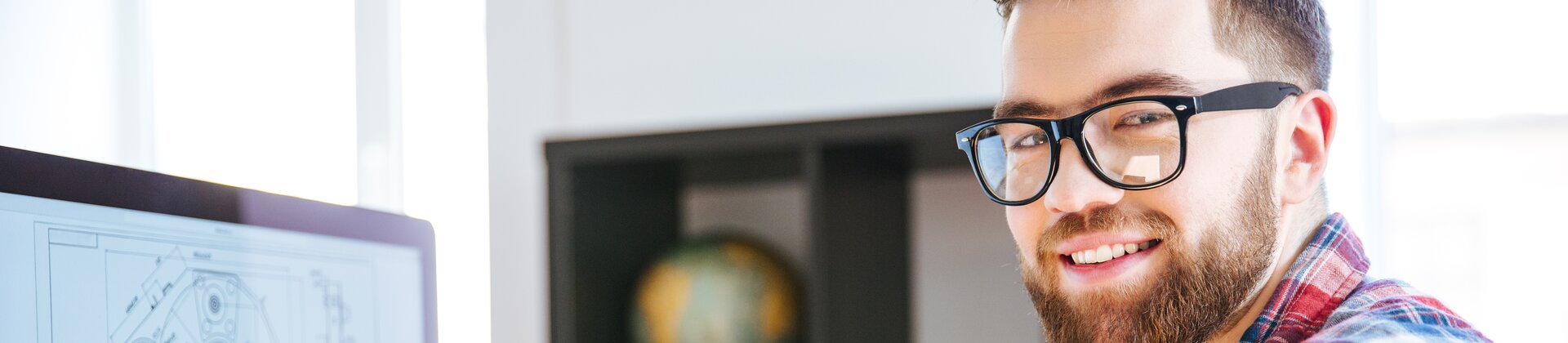 Junger Ingenieur arbeitet am Computer an technischen CAD-Zeichnungen im modernen Büro