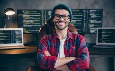 IT-Spezialist sitzt vor Monitoren mit Programmcode – Weiterbildung Datenschutz bei der IHK Akademie München zur sicheren Verarbeitung personenbezogener Daten.