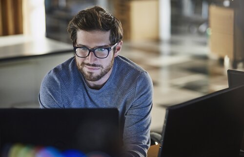IT-Mitarbeiter arbeitet konzentriert am Laptop in modernem Büro.