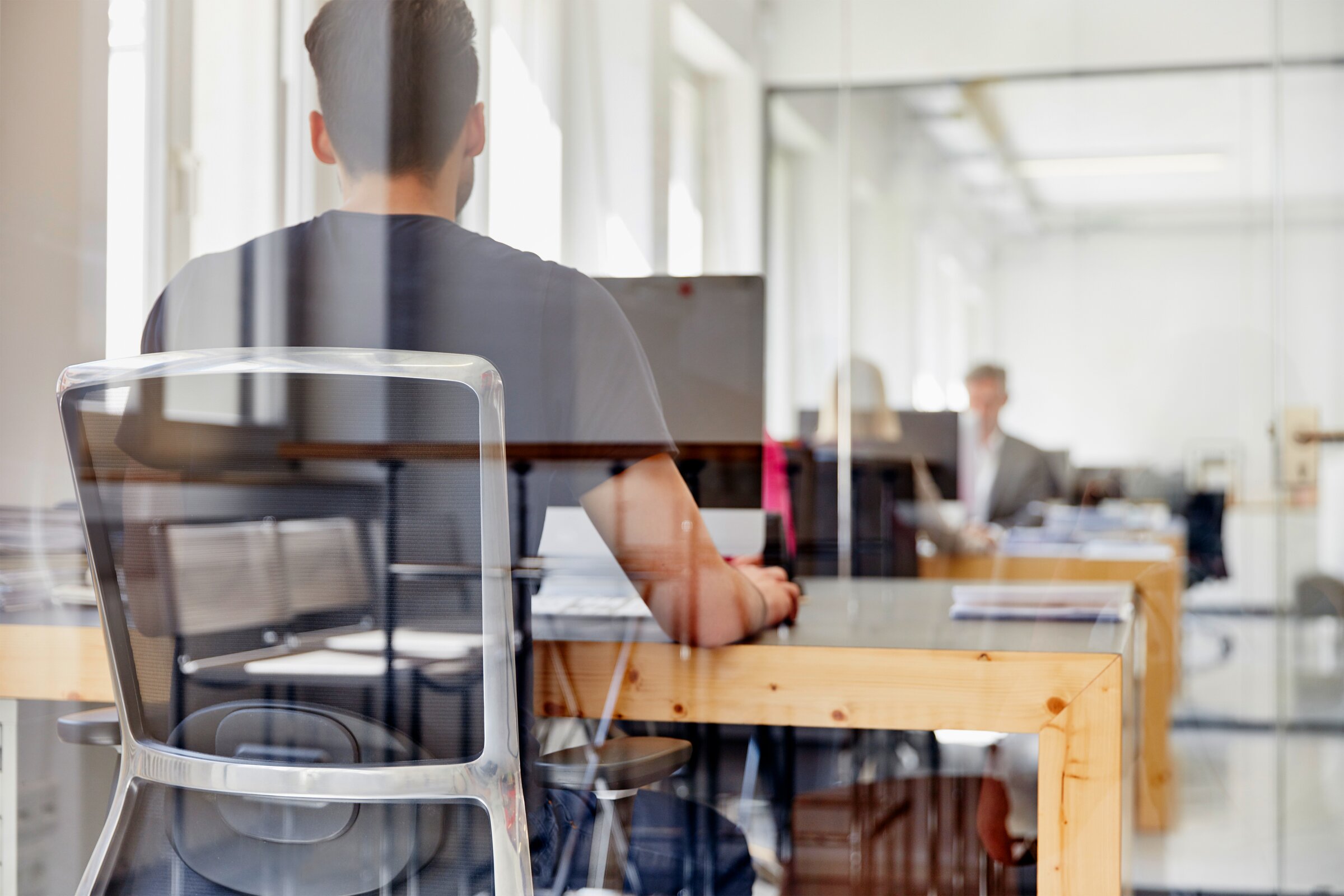 Ein Mann arbeitet in einem offenen Büro an seinem Schreibtisch – Darstellung des verantwortungsvollen Umgangs mit Kundendaten und digitaler Informationssicherheit.