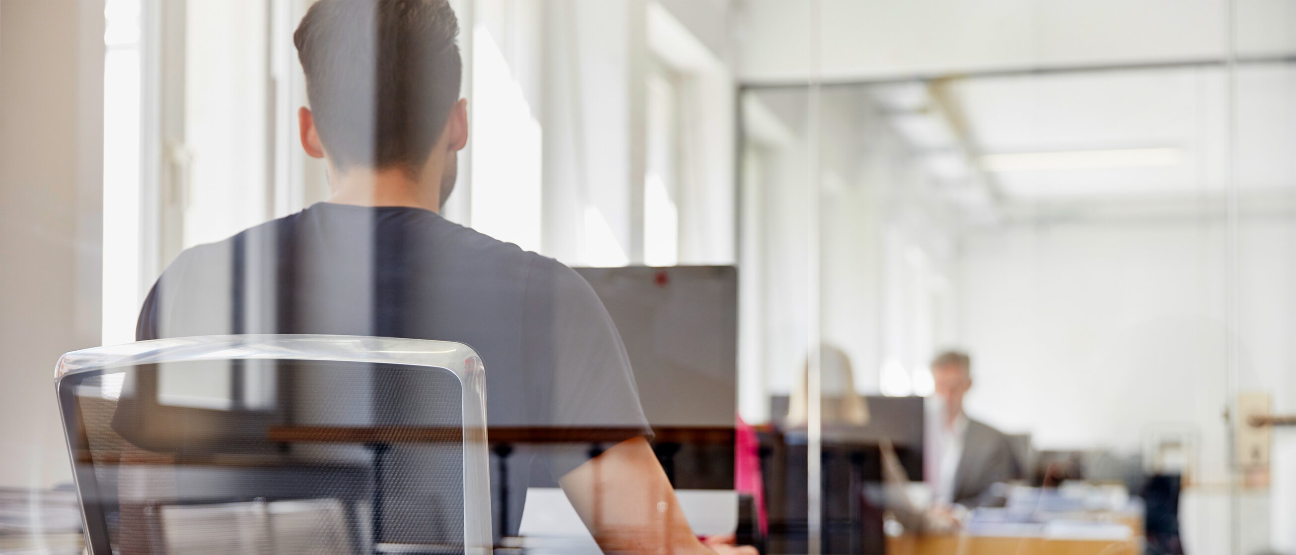 Teilnehmer einer Weiterbildung sitzt in einem Übungsraum vor einem PC und arbeitet. 