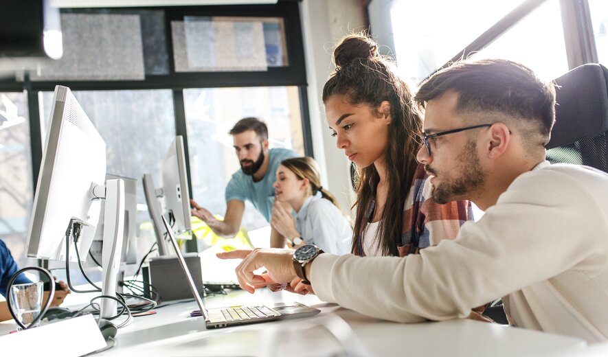 Team junger Professionals arbeitet gemeinsam an Computern in modernem Büro