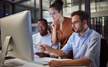 IT-Experten diskutieren über ein Thema vor einem PC. 