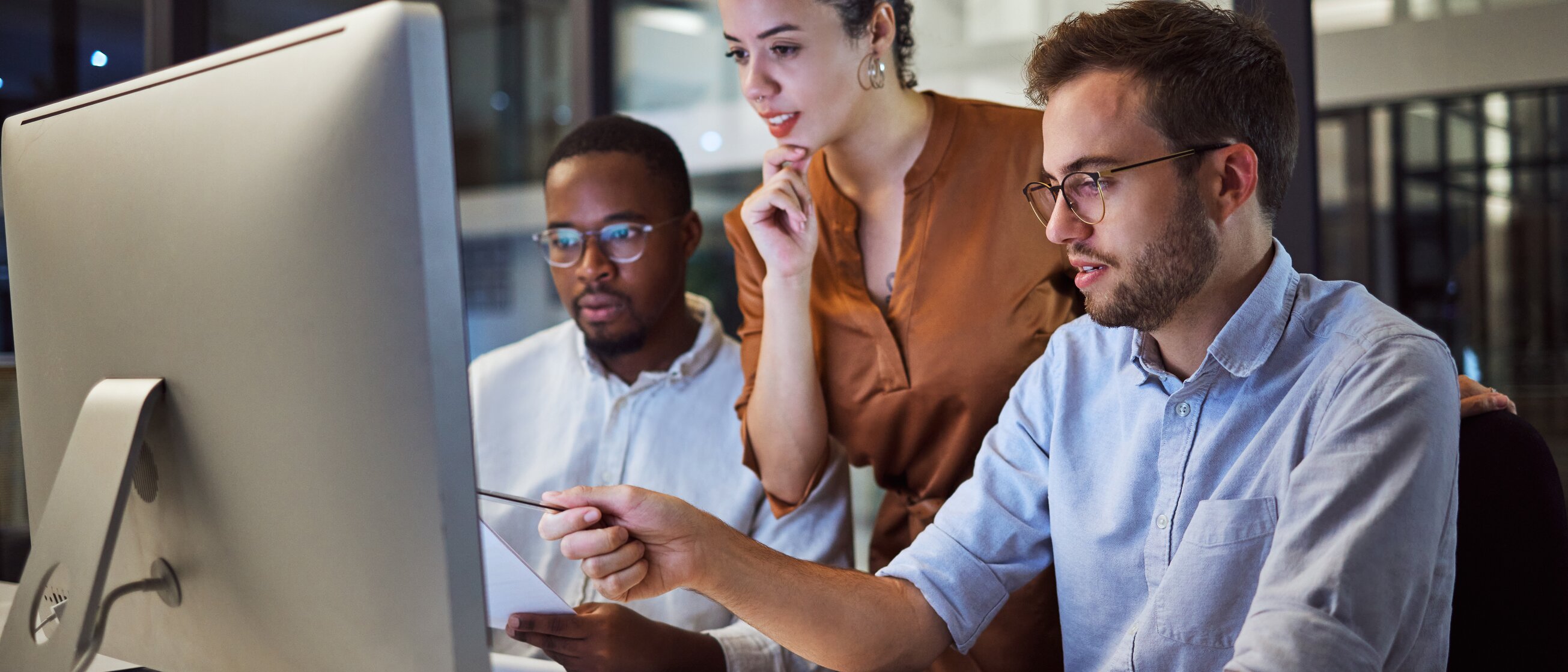 Drei Fachkräfte arbeiten gemeinsam am Computer an Sicherheitskonzepten – Weiterbildung Informationssicherheit bei der IHK Akademie München.