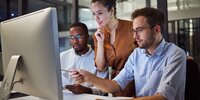 Team von IT-Mitarbeitern arbeitet gemeinsam an einem Computerprojekt im modernen Büro.