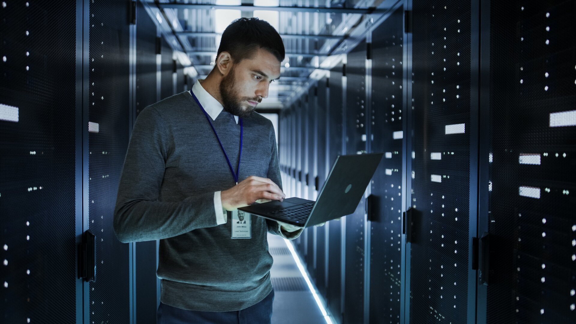 IT-Techniker überprüft Serverracks im Rechenzentrum mit Laptop