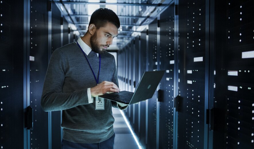IT-Techniker überprüft Serverracks im Rechenzentrum mit Laptop