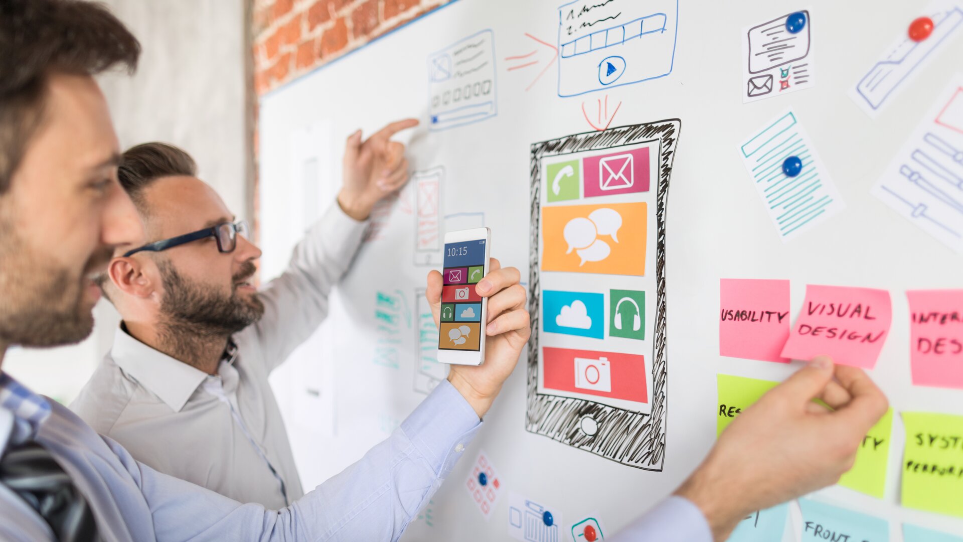 Zwei UX-Designer entwickeln eine mobile App und planen das Interface auf einem Whiteboard.