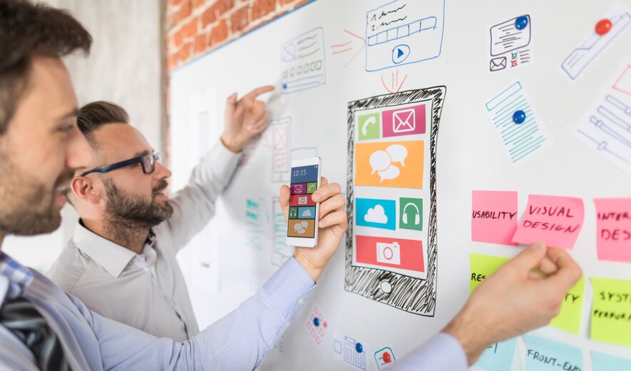 Zwei UX-Designer entwickeln eine mobile App und planen das Interface auf einem Whiteboard.