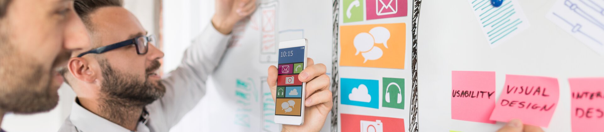 Zwei UX-Designer entwickeln eine mobile App und planen das Interface auf einem Whiteboard.