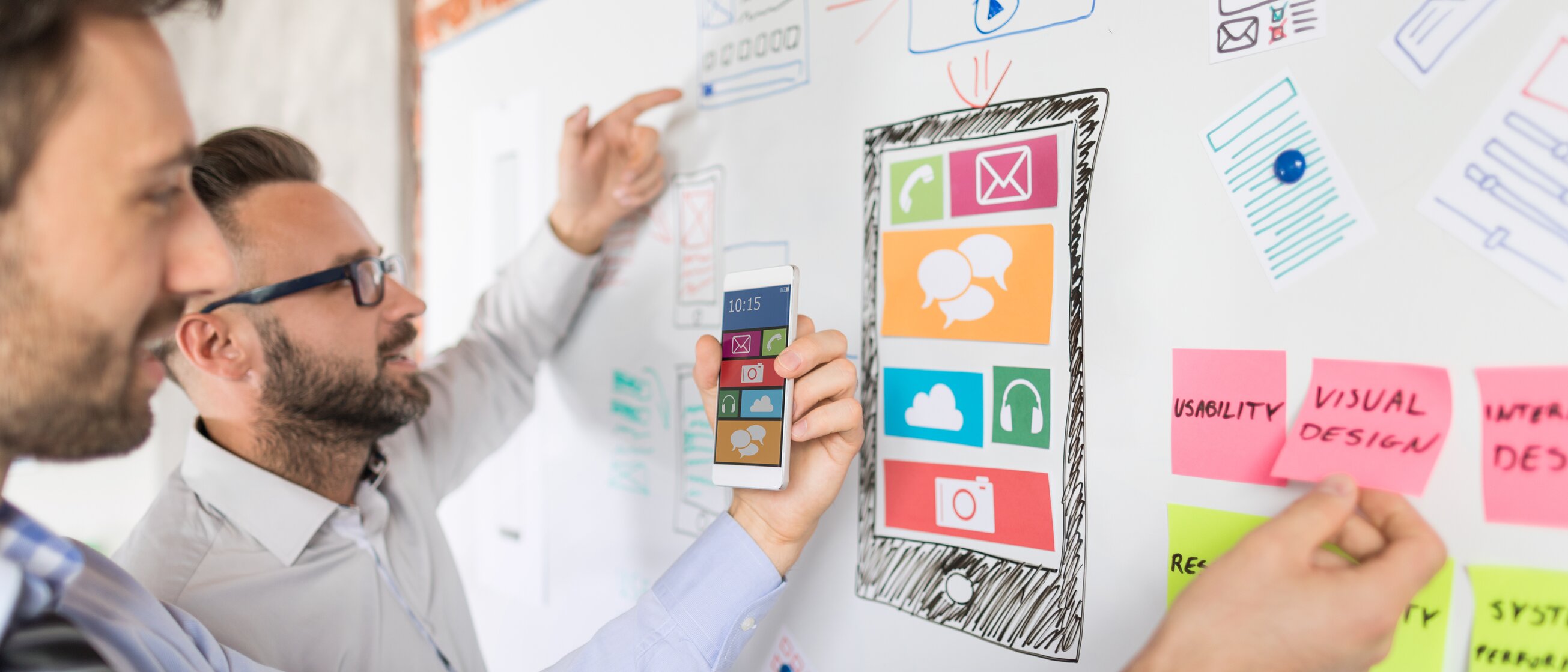 Marketingteam entwickelt Strategiekonzept am Whiteboard mit App-Design