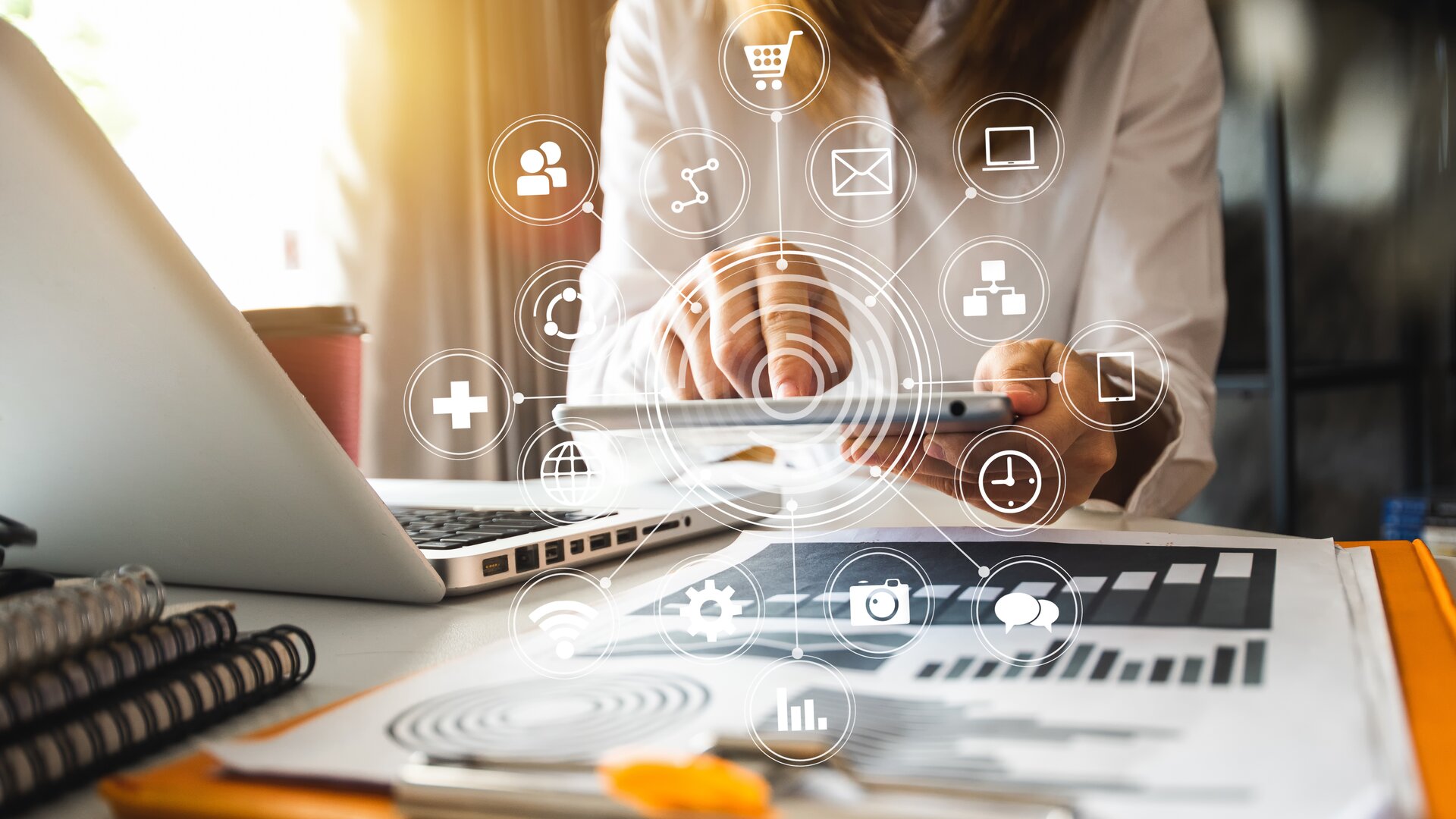 Eine Person arbeitet digital vernetzt mit Tablet und Laptop an Marketing- und Analyseprozessen.