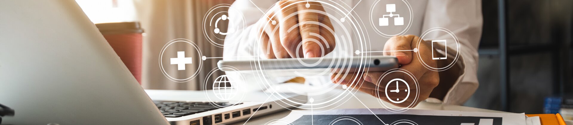 Eine Person arbeitet digital vernetzt mit Tablet und Laptop an Marketing- und Analyseprozessen.