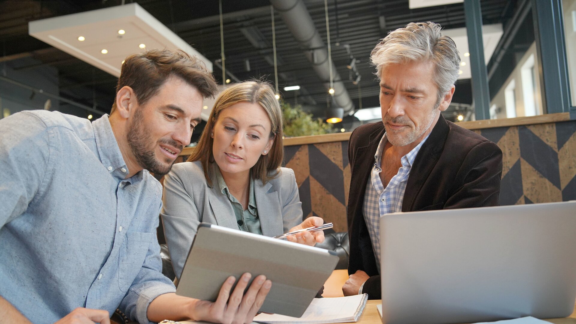 Geschäftsleute besprechen digitale Unterlagen am Tablet in moderner Büroumgebung