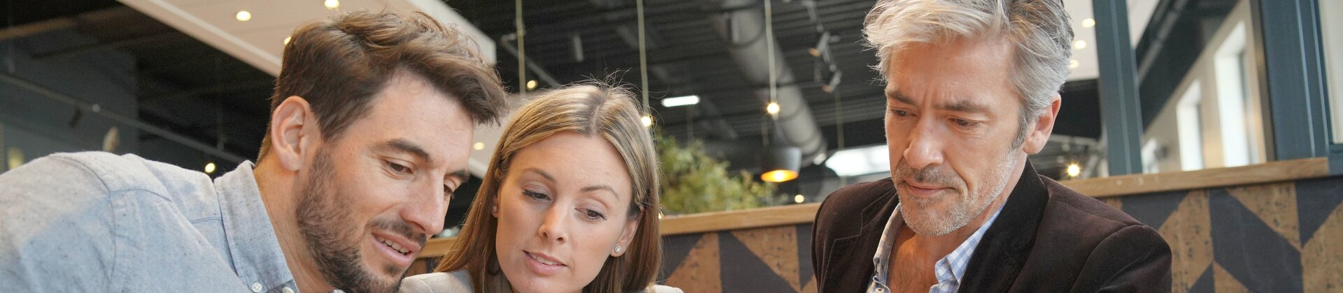 Geschäftsleute besprechen digitale Unterlagen am Tablet in moderner Büroumgebung