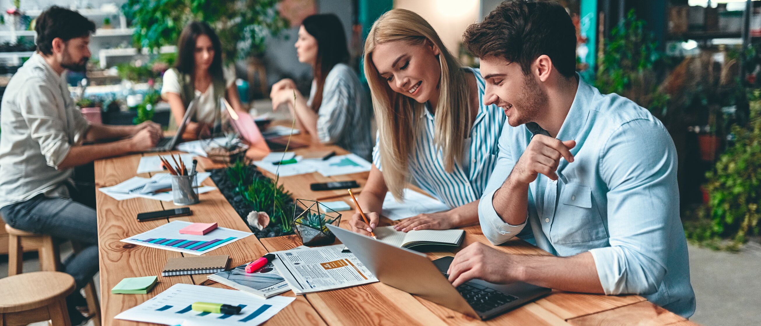 eilnehmende einer Social-Media-Weiterbildung der IHK Akademie München arbeiten gemeinsam an Laptop und Smartphone an modernen Kommunikationsstrategien.