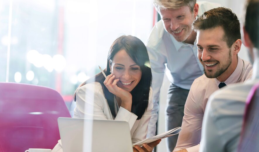 Ein Team arbeitet motiviert und konzentriert zusammen an einem Laptop.
