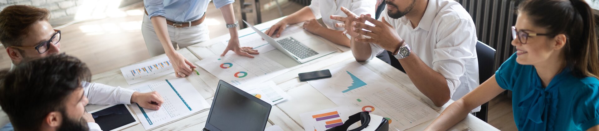 Teammeeting mit junger Gruppe, die gemeinsam Daten und Diagramme analysiert und digitale Tools nutzt