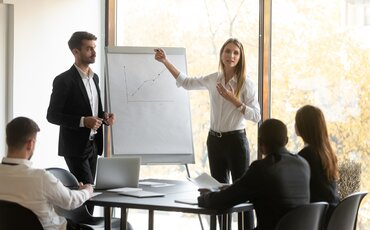 Weiterbildungen im Bereich Vertrieb: Trainerin präsentiert Verkaufsstrategien und Vertriebsanalysen vor einem Business-Team.
