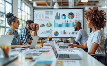 Teilnehmende einer Marketing-Weiterbildung der IHK Akademie München analysieren Diagramme und entwickeln kreative Strategien für erfolgreiche Kampagnen.