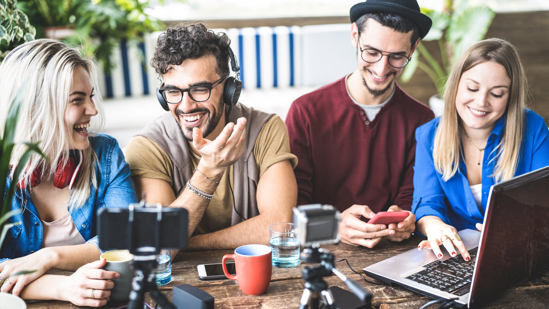 Gruppe junger Content-Creator beim gemeinsamen Produzieren von Social-Media-Inhalten am Tisch