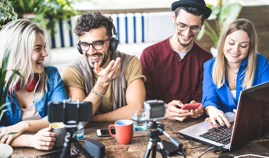 Gruppe junger Content-Creator beim gemeinsamen Produzieren von Social-Media-Inhalten am Tisch