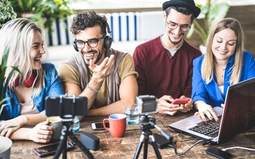 Lernende in einer Social-Media-Weiterbildung der IHK Akademie München planen Content und Strategien für erfolgreiche Online-Kommunikation mit Laptop und Kamera.