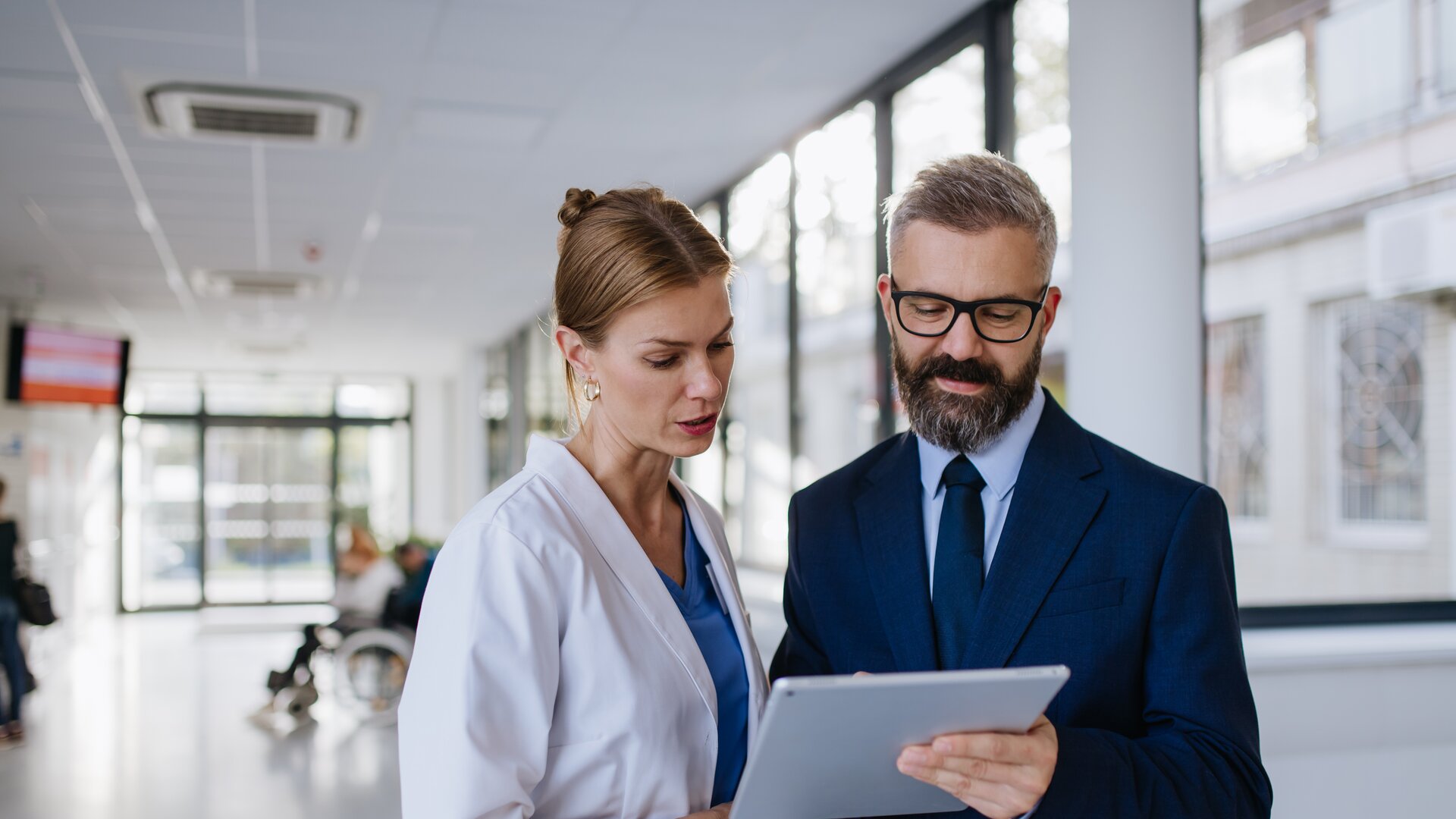 Ärztin und Geschäftsmann besprechen daten auf einem Tablet im Krankenhaus