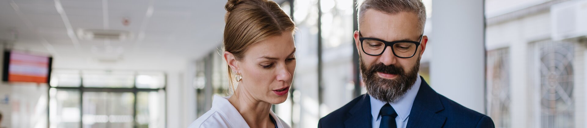 Ärztin und Geschäftsmann besprechen daten auf einem Tablet im Krankenhaus