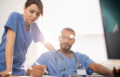 Weiterbildung im Projektmanagement: Eine Gruppe von Projektmitarbeitenden sitzt an einem Tisch und ein junger Mann schreibt etwas auf einen Post-It, der auf dem Tisch liegt. 