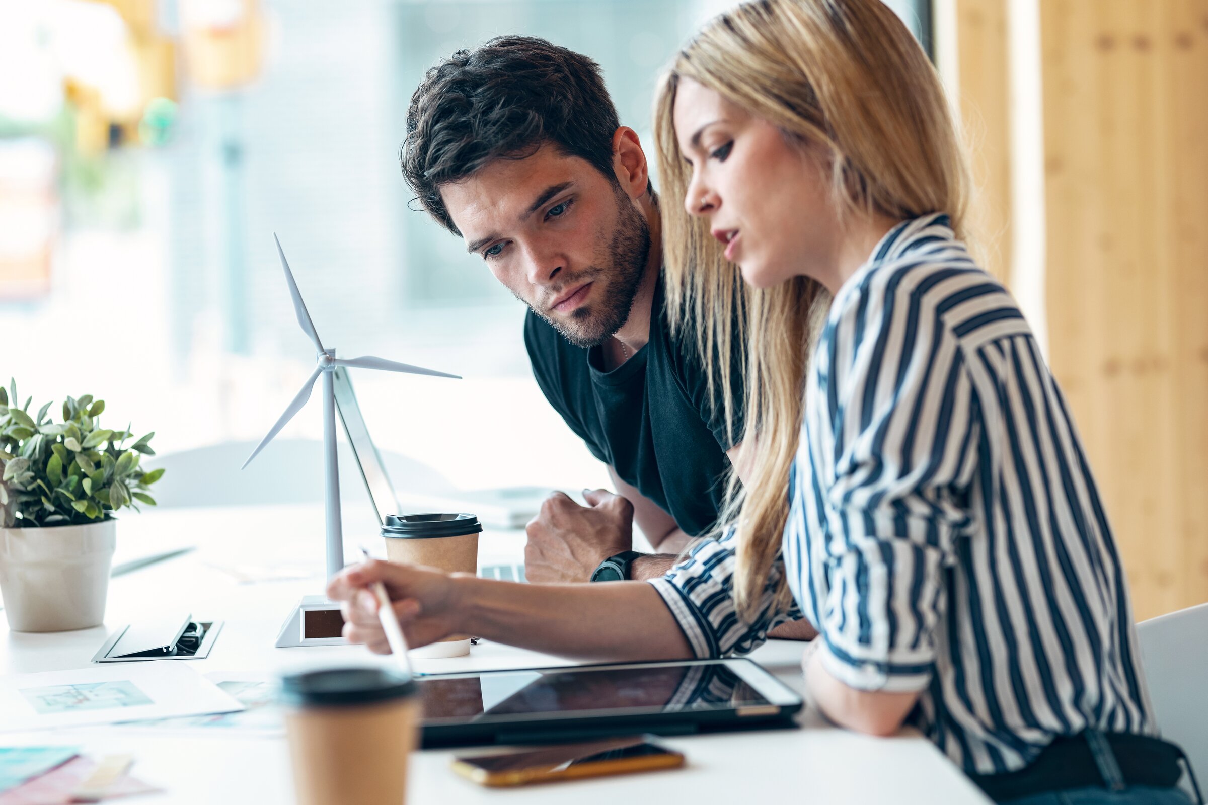 Zwei Fachkräfte arbeiten an Umwelt- und Klimamanagement mit Windradmodell – IHK Ratgeber zu Umwelt- und Lieferkettenpflichten